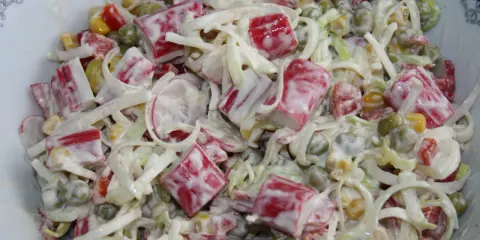 Pyszna sałatka z paluszkami surimi, groszkiem, kukurydzą i porem, polana kremowym sosem.