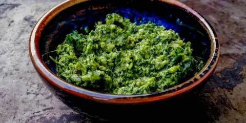 Domowe pesto z bazylii i czosnku, z dodatkiem orzechów, w ceramicznej misce. Idealne do makaronu. Jakie orzechy do pesto?