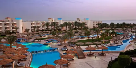 Luksusowy long beach resort Hurghada z basenami, palmami i widokiem na morze.