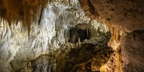 Wnętrze jaskini mroźnej, pełne stalaktytów i stalagmitów. Kamienne nacieki tworzą fantastyczne formy, a ciemne przejścia zapraszają do eksploracji.