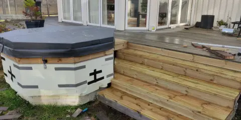 Pågår arbete med att bygga in badtunna i altan. En ny trappa i trä leder upp till altanen.