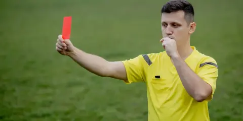 Arbitre siffle et brandit un carton rouge, signalant une faute grave. Il faut bien conjuguer "enfreindre" pour éviter ce genre de situation.