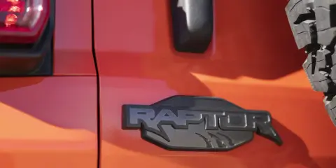 Pomarańczowy lakier lśni, a czarne, wyraziste logo "RAPTOR" z pazurami podkreśla jego dziką naturę.