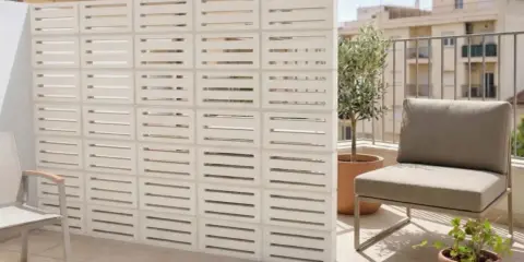 Modernos bloques de hormigón blanco crean un separador de ambiente, una de las mejores tapar balcon ideas. Un sillón y plantas completan el espacio.