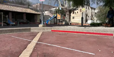 Un parque infantil con toboganes y columpios, evocando los **juegos de antes en la calle**. Un hombre pasea a su perro.