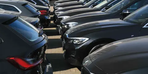 Reihe von dunklen Gebrauchtwagen, die auf einem Parkplatz stehen.
