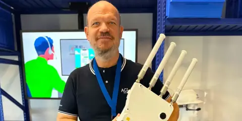 Un homme souriant tient un appareil avec quatre antennes, prêt à optimiser votre reseau wifi.