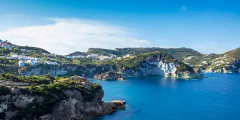 Panoramica della **cala dell'acqua a Ponza**, con case colorate aggrappate alla collina e un mare blu intenso.