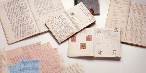 Manuscritos y diarios abiertos, como el diario de Ana Frank resumen, con escritura a mano y pequeñas ilustraciones.