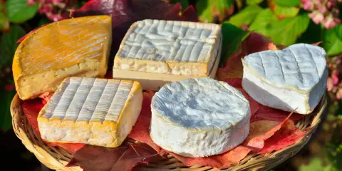 Assortiment de fromages, dont un en forme de cœur, évoquant les spécialités culinaires de Rouen.