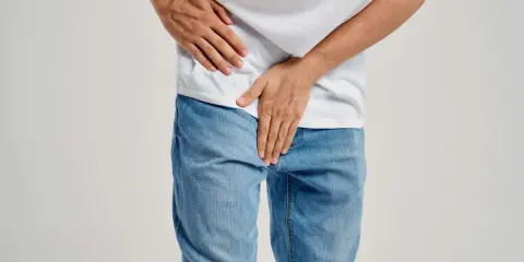Mężczyzna trzyma się za podbrzusze, co może sugerować zapalenie prostaty objawy.
