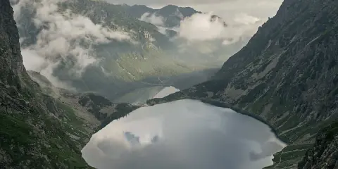 Widok na Morskie Oko, droga na Rysy w oddali. Mgła otula szczyty, odbijając się w tafli jeziora.