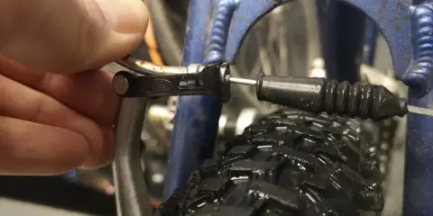 Dłoń reguluje linkę hamulca v-brake, by wyeliminować piszczące hamulce w rowerze.
