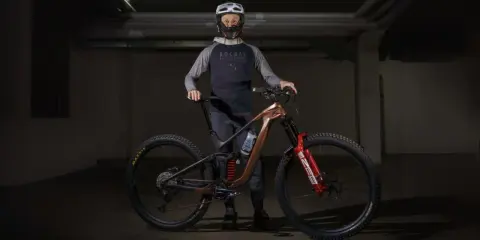 Kolarz w kasku i odzieży rowerowej prezentuje nowoczesny rower MTB. To sprzęt do ekstremalnej jazdy, a rowery mtb co to znaczy? To rowery górskie do trudnych tras.