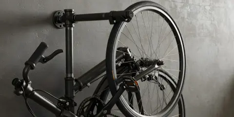 Czarny rower wiszący na ścianie na industrialnym wieszaku. Prosty sposób, jak powiesić rower na ścianie, oszczędzając miejsce.