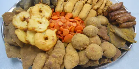 Vassoio con vari piatti tipici torinesi: frittelle, verdure, polpette e salumi.