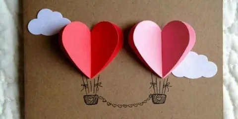 Due cuori a mongolfiera, perfetti per la festa della mamma lavoretti creativi. Nuvole bianche e un filo di cuoricini completano il disegno.