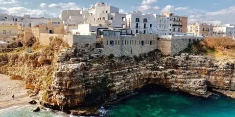 Scogliere mozzafiato e case bianche a picco sul mare turchese, perfetti **posti da visitare in Puglia estate**.