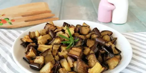Melanzane in friggitrice ad aria, dorate e saporite, pronte per essere gustate. Un rametto di rosmarino le impreziosisce.