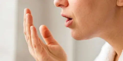 Person kollar andedräkten genom att blåsa i handen. Kanske en svamp i munnen kan hjälpa?
