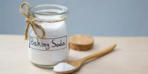 Słoik z napisem "Baking Soda" i drewniana łyżka z proszkiem. To naturalny sposób na usuwanie plam.