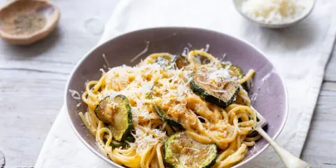 Pyszny makaron z cukinią i pieczarkami, posypany parmezanem. Idealny lekki obiad.