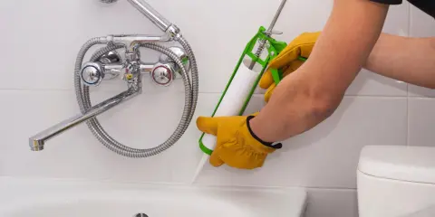 Person dichtet mit Silikon ab, um Gerüche zu entfernen.