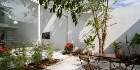 Un patio moderno con mesa y sillas de madera, flores y un árbol. ¡Excelentes ideas para porches pequeños y acogedores!
