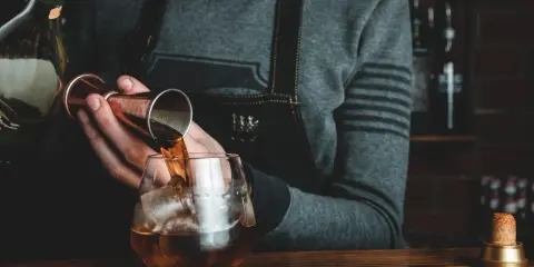 Barman nalewa whisky Glenlivet 12 do szklanki z lodem. Wiele pozytywnych opinii potwierdza jej jakość.