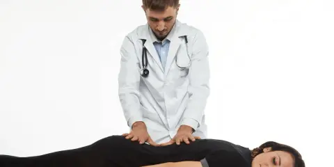 Terapeuta wykonuje delikatne ruchy na plecach pacjentki, co ilustruje, na czym polega terapia Bowen'a.