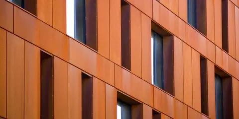 Fachada de edificio revestida con paneles de acero corten, creando un efecto oxidado y moderno.