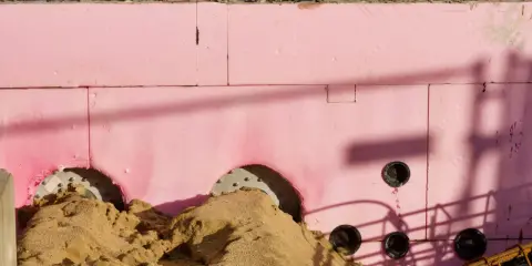 Aislamiento rosa con agujeros para tuberías y montones de arena. Se aprecian sombras y orientaciones cte.