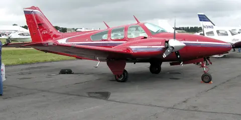 Roter Beechcraft Baron mit zwei Propellern auf dem Flugplatz.