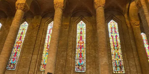 Vitraux colorés illuminant l'intérieur de l'église de Gien, encadrés par de hautes colonnes de briques.