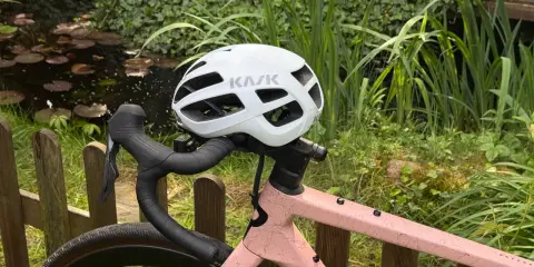 Biały kask rowerowy KASK na kierownicy różowego roweru. Przygotowany do jazdy, zgodnie z przepisami ruchu drogowego dla rowerzystów.