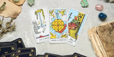 Karta życia tarot: As Mieczy, Koło Fortuny i Król Buław. Tajemnicze kryształy i stare księgi dopełniają mistyczną atmosferę.