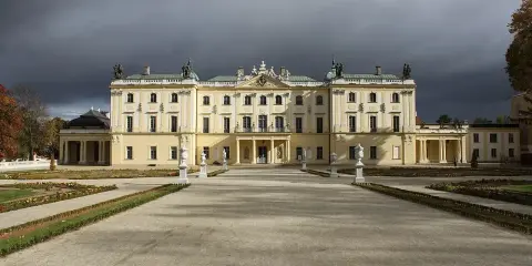 Pałac Branickich w Białymstoku, majestatyczna budowla z ogrodem, pod burzowym niebem.