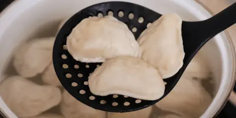 Gotowanie mrożonych pierogów: wyjęte z wrzątku na cedzaku, gotowe do podania.