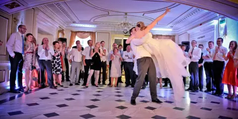 Para młoda wiruje w tańcu, goście patrzą z zachwytem. To piękny moment, jak bachata taniec.