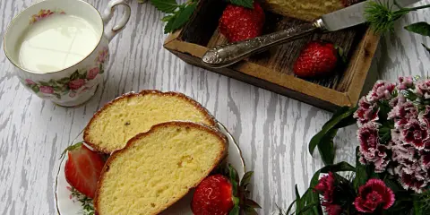 Pyszne ciasto z żółtek, udekorowane cukrem pudrem i truskawkami, podane z mlekiem.