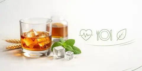 Szklanka whisky z lodem, butelka, kłosy zboża i mięta. Wyobraź sobie, że to pomieszczenie, w którym dojrzewa whisky.