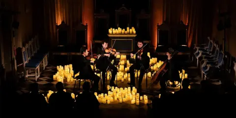 En stråkkvartett spelar bland hundratals levande ljus under en magisk candlelight concert.
