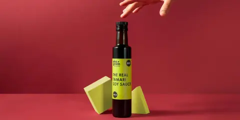Butelka sosu tamari z etykietą "THE REAL TAMARI SOY SAUCE" na tle.