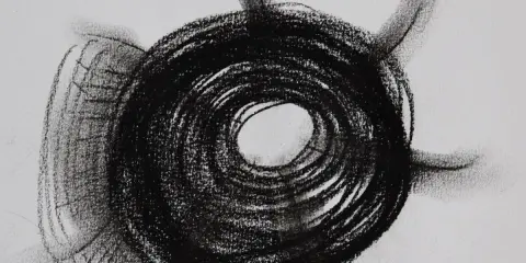 Abstract charcoal mark making examples, featuring a dark, spiraling circle with radiating lines on a white background.