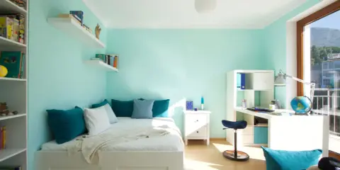 Habitación juvenil con paredes verde menta. La decoración combina tonos turquesa en cojines y accesorios, creando un ambiente fresco y moderno.