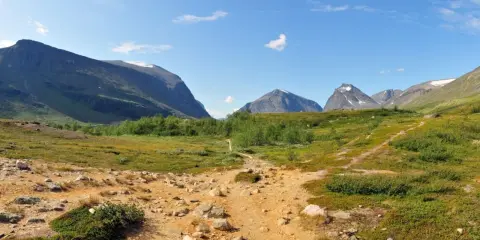 Vandringsled mot Kebnekaise, en fantastisk utsikt som gör bestiga Kebnekaise pris värt. Berg, grönska och en klarblå himmel.