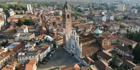 Vista aerea della Duomo di Monza, con la sua facciata a strisce bianche e nere. Si vede il campanile e il centro storico, che mostra dove si trova Monza.