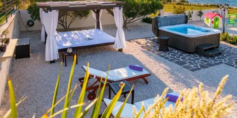 Relaks przy morzu: leżaki, jacuzzi i baldachim w chorwackim apartamencie.