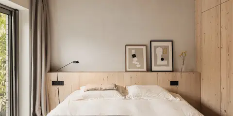 Acogedor dormitorio sin cabecero, con cama de lino, arte abstracto y armario de madera.