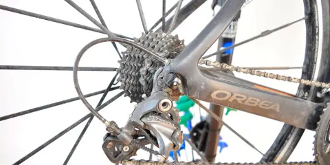 Tylna przerzutka Shimano Ultegra, kluczowy element przekładni rowerowej, na tle koła i ramy Orbea.